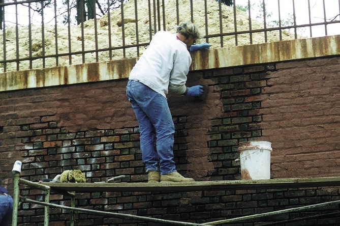 man painting a brick wall