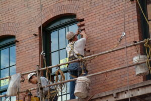 Man working on fixing the bricks: Façade Maintenance & Repair 