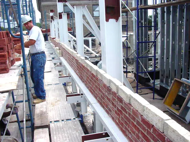 Graciano team member standing while working on brick tuckpointing